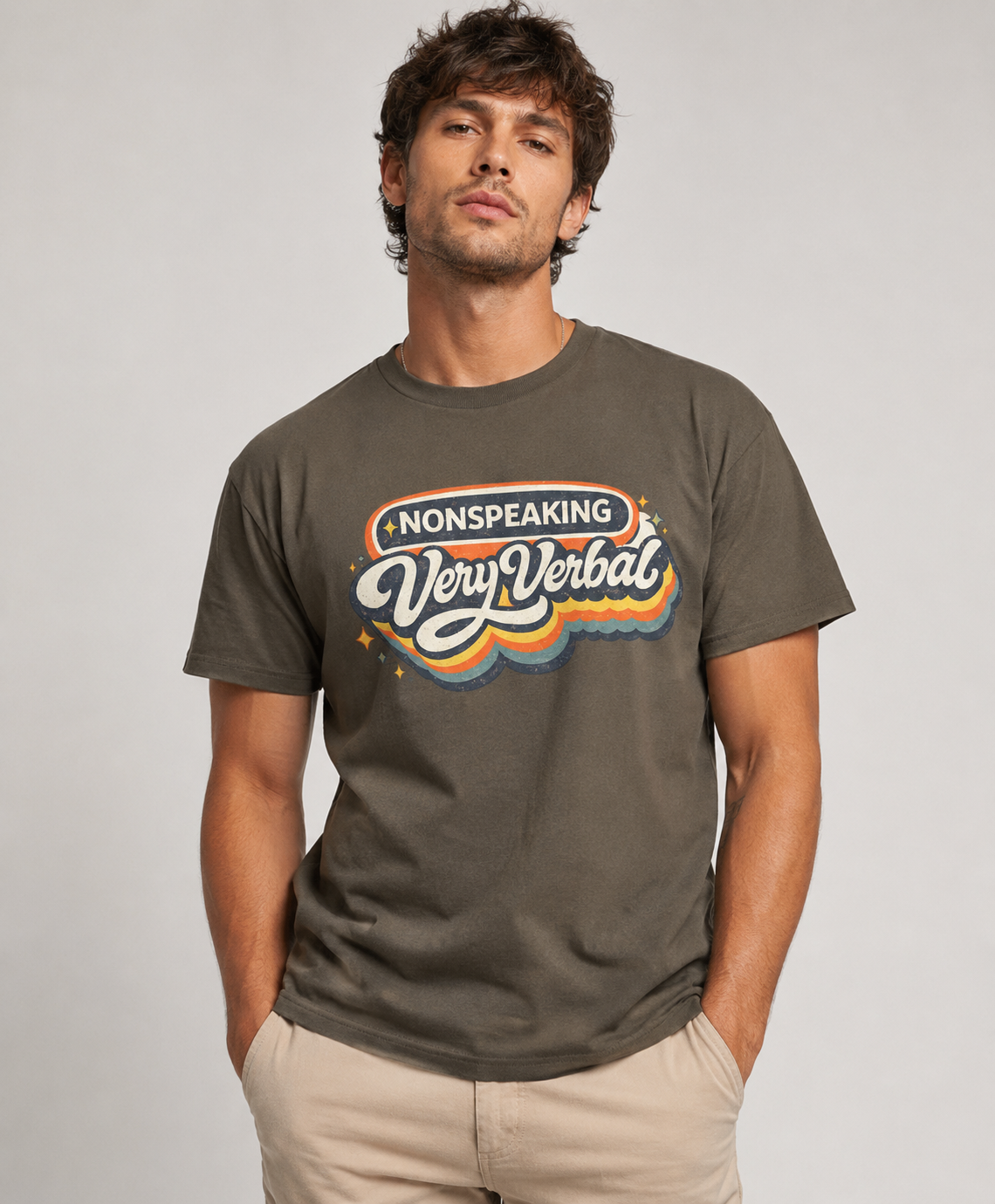 Man wearing a gray t-shirt with colorful text design on a plain background Text says nonspeaking very verbal
