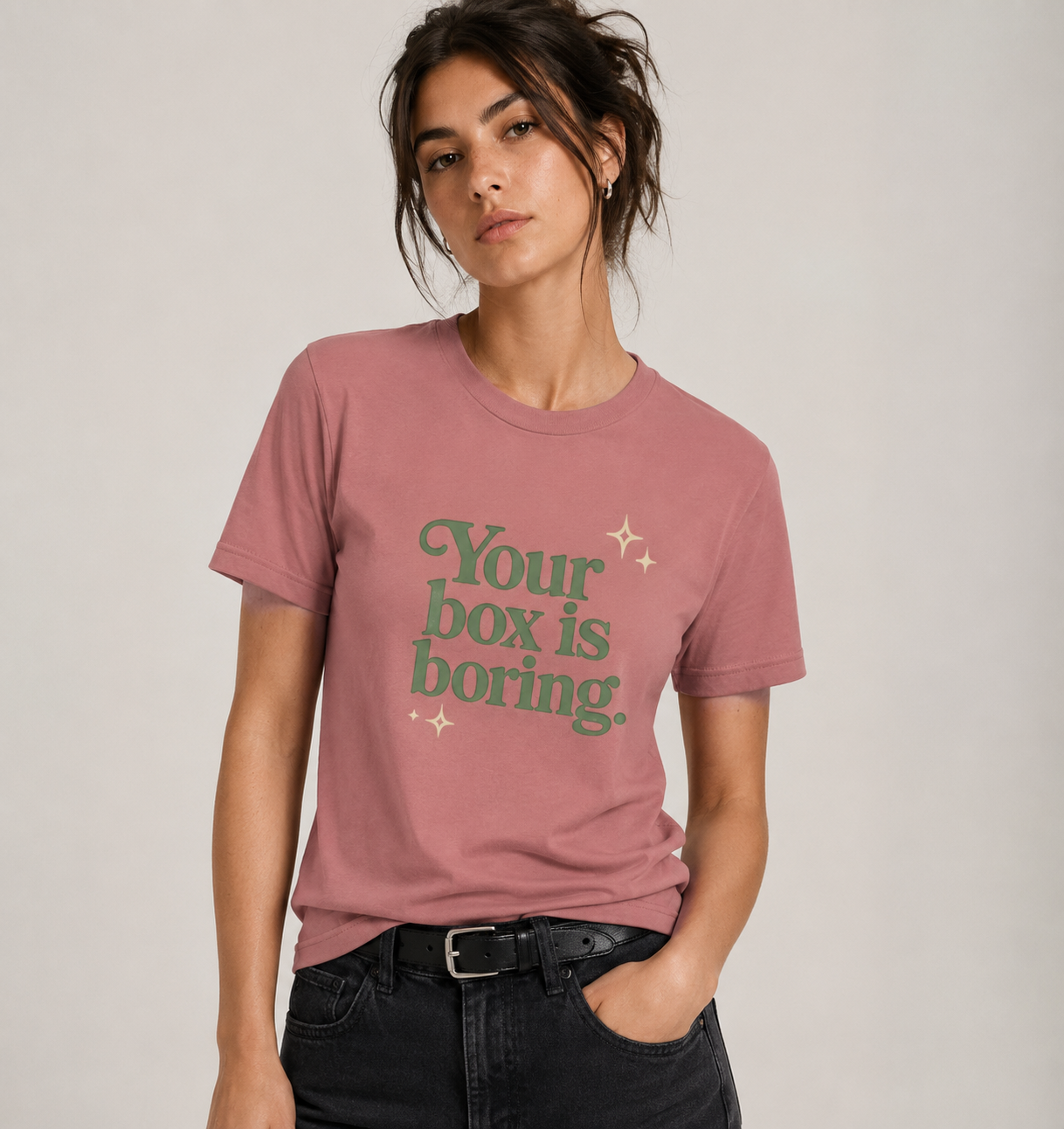 Person wearing a pink t-shirt with 'Your box is boring' text on a plain background