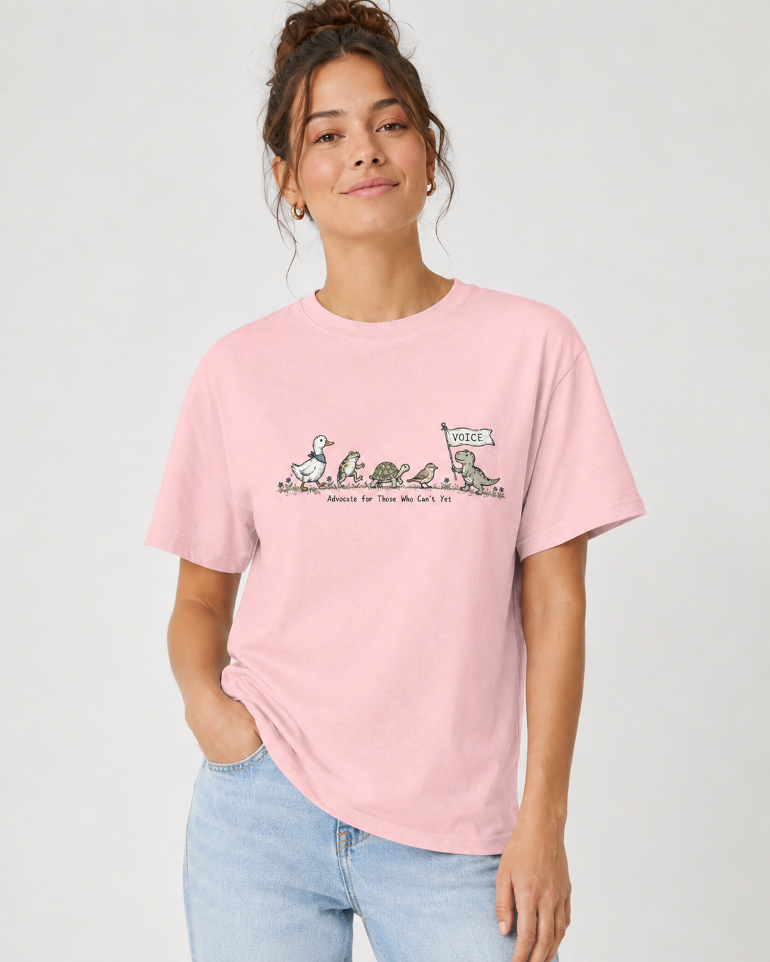 Person wearing a pink t-shirt with a graphic design on a plain background text says advocate for those who cant yet