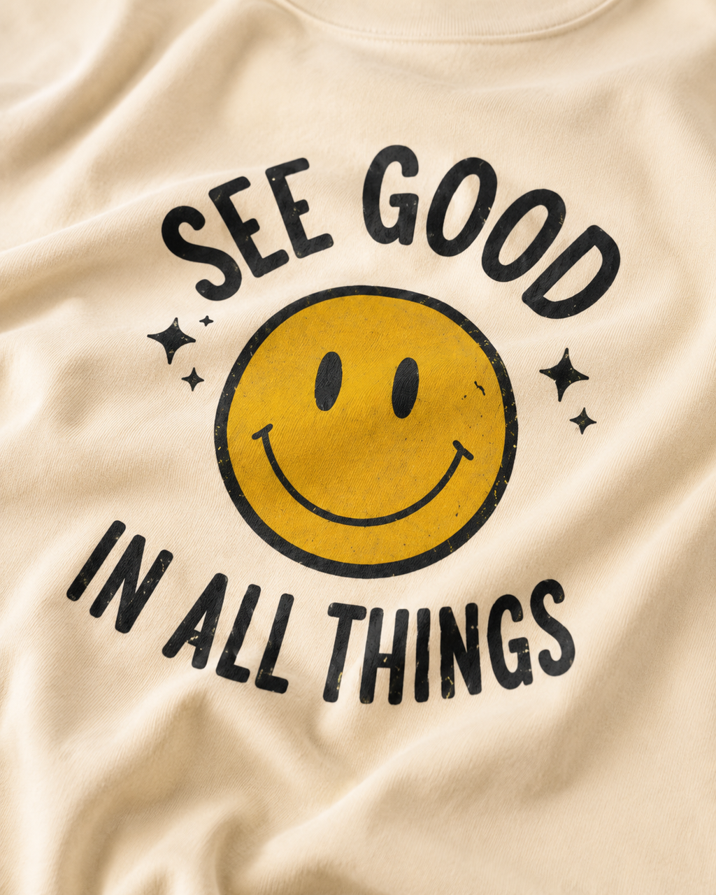 Beige fabric with a smiley face and text 'See good in all things' printed on it.