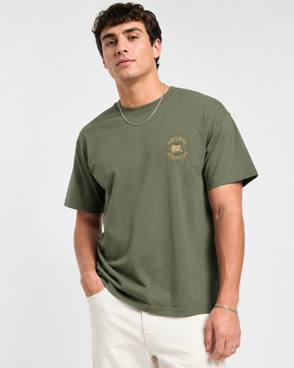 Man wearing a green t-shirt with a logo on a white background logo is brain and says dopamine detective