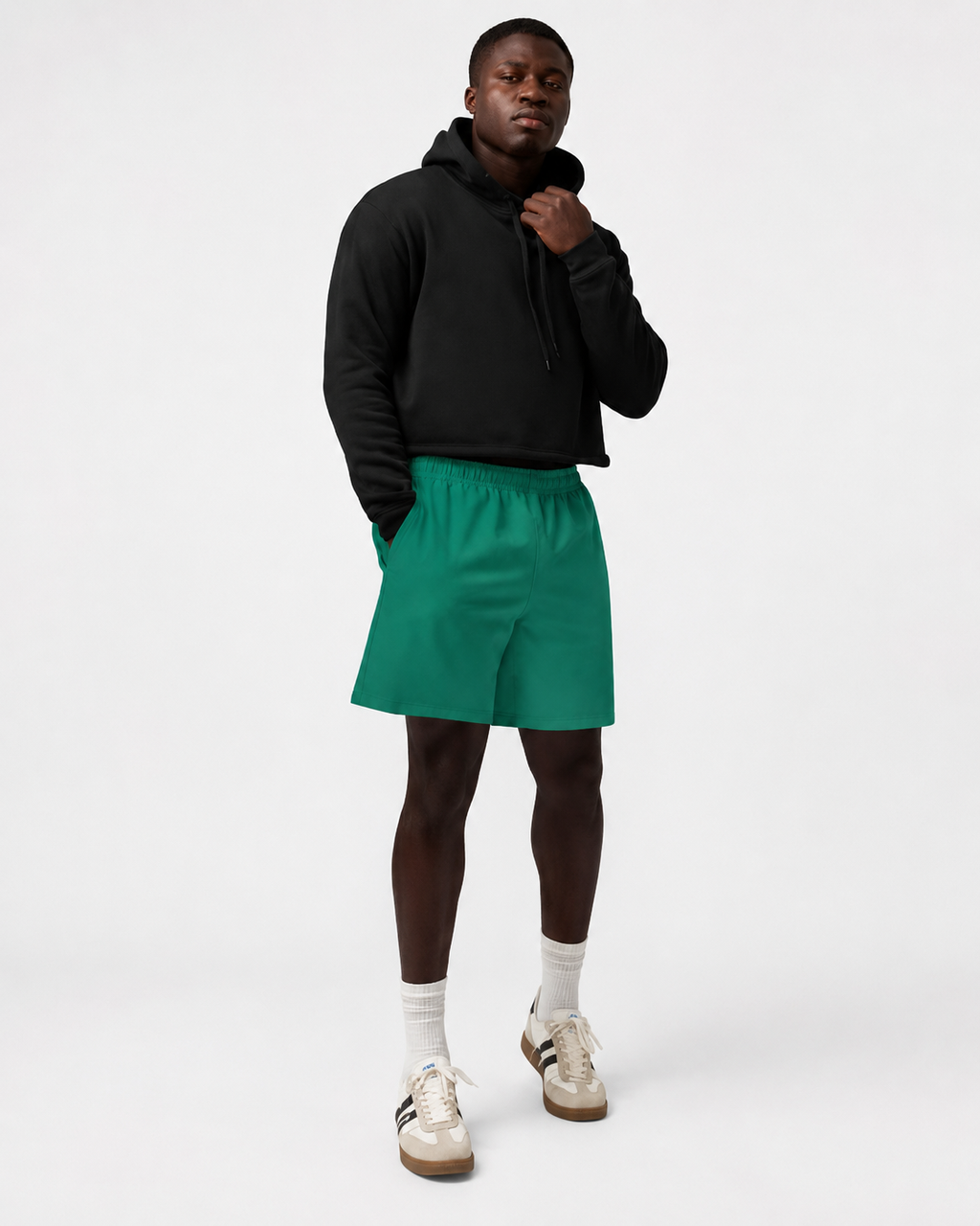 Person wearing a black hoodie and green shorts on a white background